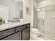 Bathroom with a granite countertop, dark wood cabinets, and a glass-enclosed shower at 2412 Tanger Dr, Kissimmee, FL 34747