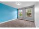 Bright bedroom with vibrant blue accent wall, two windows, and plush carpet flooring at 5144 Ravena E Ave, St Cloud, FL 34771