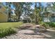 Inviting backyard featuring a brick patio, fire pit, lush greenery, and mature trees, ideal for relaxation at 519 N Clara Ave, Deland, FL 32720