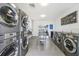 Bright community laundry room featuring rows of gray, front-loading washer and dryer units and tile flooring at 5220 Curry Ford Rd # 303, Orlando, FL 32812