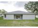 Backyard view of the home's exterior, showcasing a flat roof and sliding glass doors at 6038 Sw 154Th Place Rd, Ocala, FL 34473