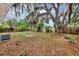 Large backyard with mature trees and a partial fence, offering ample space for activities at 6312 Appian Way, Orlando, FL 32807