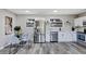 Open kitchen and dining area featuring stainless steel appliances, gray wood floors, white cabinets and drawers, and light gray walls at 6312 Appian Way, Orlando, FL 32807