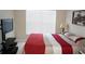 Bright bedroom featuring a large window, television, and a comfortable bed with red accents at 6453 Alcalde Ct # 104, Orlando, FL 32835