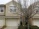 Exterior view of a tan two-story townhome with an attached single car garage at 6453 Alcalde Ct # 104, Orlando, FL 32835