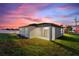 Home exterior with covered patio, lush green lawn, and a vibrant sunset backdrop at 804 Colville Dr, Kissimmee, FL 34759