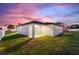 Exterior view of home with covered patio, green grass, and lush landscaping set against a vivid sunset sky at 804 Colville Dr, Kissimmee, FL 34759