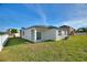 Backyard featuring a well-maintained lawn, tropical landscaping, and covered patio at 804 Colville Dr, Kissimmee, FL 34759