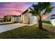 Exterior home showcasing a tropical palm, fresh landscaping, long driveway, and warm lighting at 804 Colville Dr, Kissimmee, FL 34759