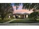 The front exterior of this house at dusk, framed by trees, features a neat lawn and walkway at 859 Windcrest Pl, Winter Springs, FL 32708