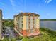 Lakefront condo building with colorful facade, tile roof, ample parking, and lush landscaping at 8743 S The Esplanade # 18, Orlando, FL 32836
