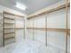 Large walk-in closet features custom wooden shelving units and gleaming marble-tiled floors at 8743 S The Esplanade # 18, Orlando, FL 32836