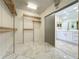 Spacious walk-in closet featuring wooden shelving and drawers, with marble-tiled floor and access to bathroom with double sink vanity at 8743 S The Esplanade # 18, Orlando, FL 32836