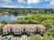Aerial view of a condo complex with a red tile roof next to a tranquil lake surrounded by lush trees at 980 Mooring Ave # 105, Altamonte Springs, FL 32714