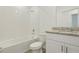 Bathroom features a combination tub and shower with white tiled walls, granite countertops and white cabinets at 4532 Windy Oak Way, St Cloud, FL 34772