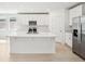 Modern white kitchen features a center island, stainless steel appliances, and ample cabinet space at 4532 Windy Oak Way, St Cloud, FL 34772