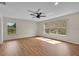 Bright bedroom with wood floors, a ceiling fan, and large windows with views of the backyard at 1037 Sailing Bay Dr, Clermont, FL 34711