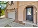 Close up of an arched entrance and garage of a two story house, with a beautifully adorned front door at 1037 Sailing Bay Dr, Clermont, FL 34711
