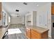 Open kitchen flows to living area with stainless appliances and wood cabinets and island at 1037 Sailing Bay Dr, Clermont, FL 34711