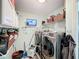 This laundry room features a washer and dryer set, shelving, storage cabinets, and a television at 104 Bentley Oaks Blvd, Auburndale, FL 33823