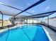 Sparkling in-ground pool surrounded by screened enclosure, patio seating, and well-manicured landscaping at 104 Bentley Oaks Blvd, Auburndale, FL 33823