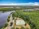 Aerial view featuring tennis courts, walking trails and a serene lake surrounded by trees at 10852 Spider Lily Dr # S, Orlando, FL 32832