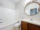 Clean bathroom with a tub, toilet, vanity with a round mirror, and fresh white fixtures at 10852 Spider Lily Dr # S, Orlando, FL 32832