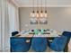 Elegant dining room with dark wood table, blue velvet chairs, and modern artwork at 1188 Challenge Dr, Davenport, FL 33896