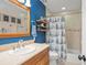 Nautical themed bathroom features a wooden cabinet, framed nautical images, and tub with matching blue and white shower curtain at 1311 Olympia Park Cir, Ocoee, FL 34761