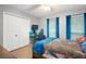 Bright bedroom with wood floor features closet, desk with gaming chair and equipment, and a blue, red, and brown bedspread at 1311 Olympia Park Cir, Ocoee, FL 34761