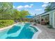 A freeform backyard pool and spa are surrounded by lush landscaping, with furniture under a blue umbrella for relaxing at 1311 Olympia Park Cir, Ocoee, FL 34761