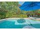 Backyard freeform pool is surrounded by tall plants and landscaping, and a blue umbrella sits atop a table and chairs at 1311 Olympia Park Cir, Ocoee, FL 34761