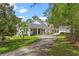 Stunning exterior of home featuring a covered portico, long driveway, and mature trees at 1417 Olympia Ave, Mount Dora, FL 32757