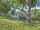 Exterior of home with a screened lanai surrounded by mature trees and landscaping at 1551 Sherbrook Dr, Clermont, FL 34711