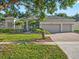 Charming single-story home featuring lush landscaping and a brick-paved driveway leading to a three-car garage at 1551 Sherbrook Dr, Clermont, FL 34711
