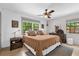 Bright main bedroom featuring a ceiling fan, wood floors, a patterned rug, and views of mature trees at 1558 Regal Oak Dr, Kissimmee, FL 34744