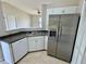 Bright kitchen featuring stainless steel refrigerator, white cabinets, and tile floor at 2431 Lackland Dr, Deltona, FL 32738