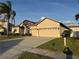 Beige home with a three-car garage and well-maintained landscaping at 2715 Bartlet Dr, Kissimmee, FL 34741