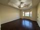 Spacious main bedroom featuring dark wood floors, a tray ceiling with fan, and bright windows at 2715 Bartlet Dr, Kissimmee, FL 34741