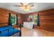 This bedroom features warm wood paneling, a ceiling fan, and abundant natural light from two windows at 290 Pine St, Ormond Beach, FL 32174