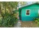 The covered porch leads to a vibrant home exterior surrounded by lush plants at 290 Pine St, Ormond Beach, FL 32174