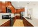 Modern kitchen with stainless steel appliances, wooden cabinets, a center island, and tile backsplash at 3053 Brook Stone Ter, Davenport, FL 33837