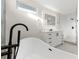 Bathroom showcasing a modern vanity with an illuminated mirror, and a soaking tub with elegant black fixtures at 4087 Clock Tower Dr, Port Orange, FL 32129