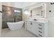 Elegant bathroom featuring a sleek soaking tub, illuminated mirror, and modern vanity with dark hardware at 4087 Clock Tower Dr, Port Orange, FL 32129