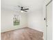 Bright bedroom with wood-look flooring, a ceiling fan, and a window overlooking the neighborhood at 4087 Clock Tower Dr, Port Orange, FL 32129