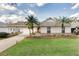 Charming home boasts a well-manicured lawn, complete with palm trees and a covered driveway with garage at 4087 Clock Tower Dr, Port Orange, FL 32129