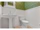 Charming powder room featuring a pedestal sink, white wainscoting, and black and white tile flooring at 525 Sheridan Blvd, Orlando, FL 32804
