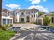 Elegant home featuring a paver driveway with water features, arched entry, and multiple garage bays at 6137 Grosvenor Shore Dr, Windermere, FL 34786