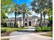 Stately two-story home with lush landscaping and a circular driveway lined with towering palm trees at 6137 Grosvenor Shore Dr, Windermere, FL 34786