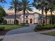 Elegant two-story home with a circular driveway, lush landscaping, and a view of the sunset at 6137 Grosvenor Shore Dr, Windermere, FL 34786
